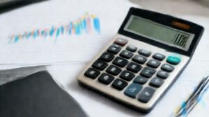 Professional calculator displaying agency profit metrics with financial charts in background.